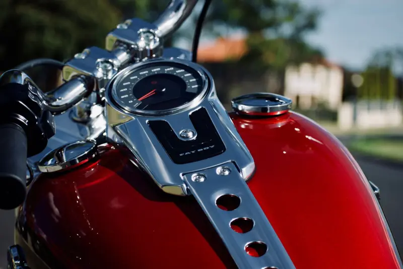 Close-up van een rode motortank met chromen tankdop en klokje